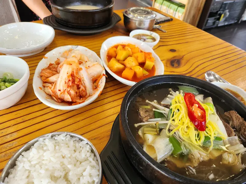 테이블 위에 놓인 갈비탕, 김치, 깍두기, 밥