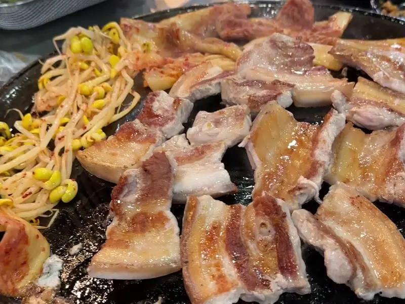 불판 위에 올려진 삼겹살과 콩나물