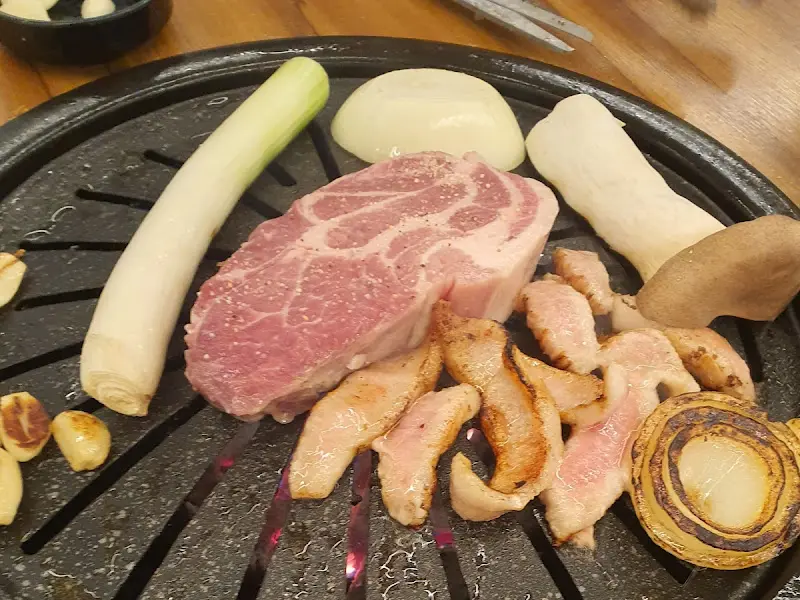 숯불 위에서 익어가는 흑돼지 오겹살과 채소