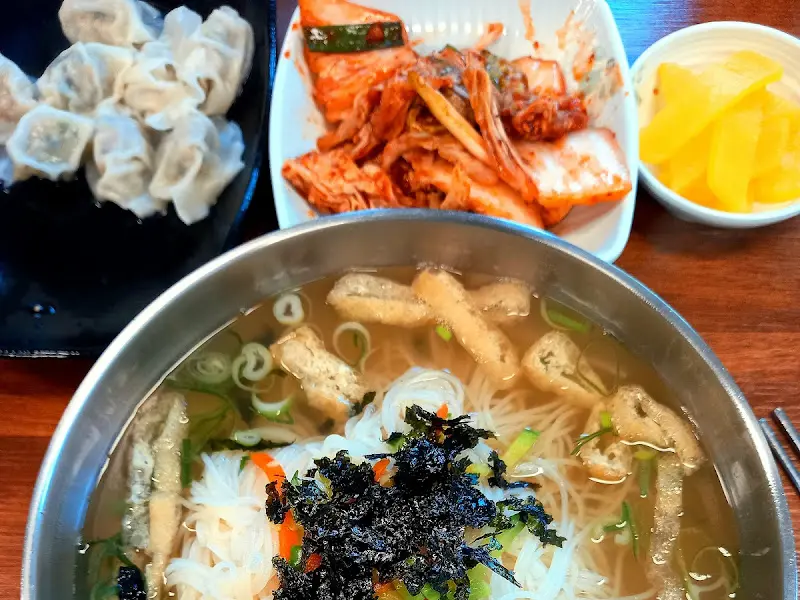 잔치국수와 물만두, 김치, 단무지가 함께 놓인 테이블