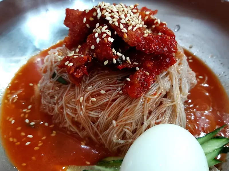 코다리 냉면의 클로즈업 샷. 붉은 양념에 버무려진 코다리와 깨가 식욕을 자극한다.