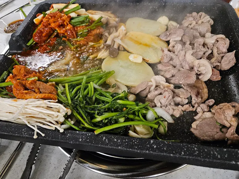 불판 위에서 익어가는 오리고기와 미나리