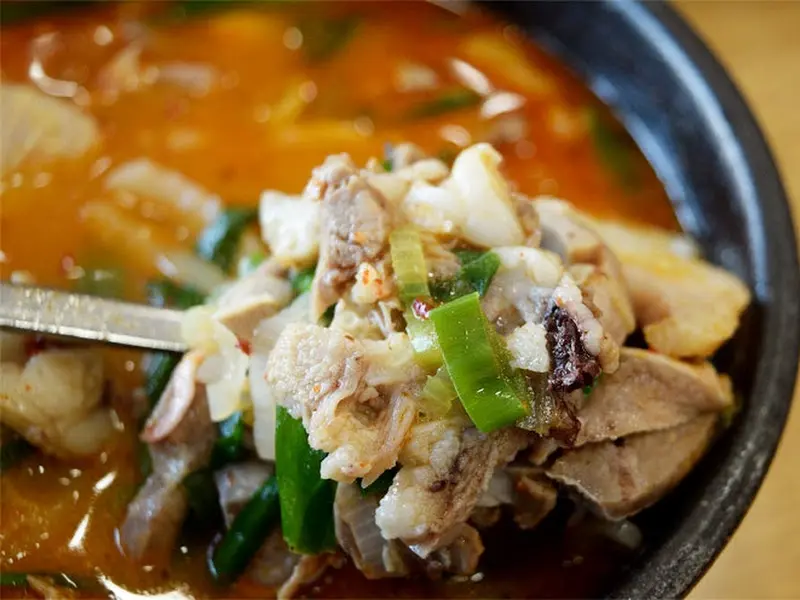 숟가락 위에 푸짐하게 담긴 순대와 고기, 야채의 조화