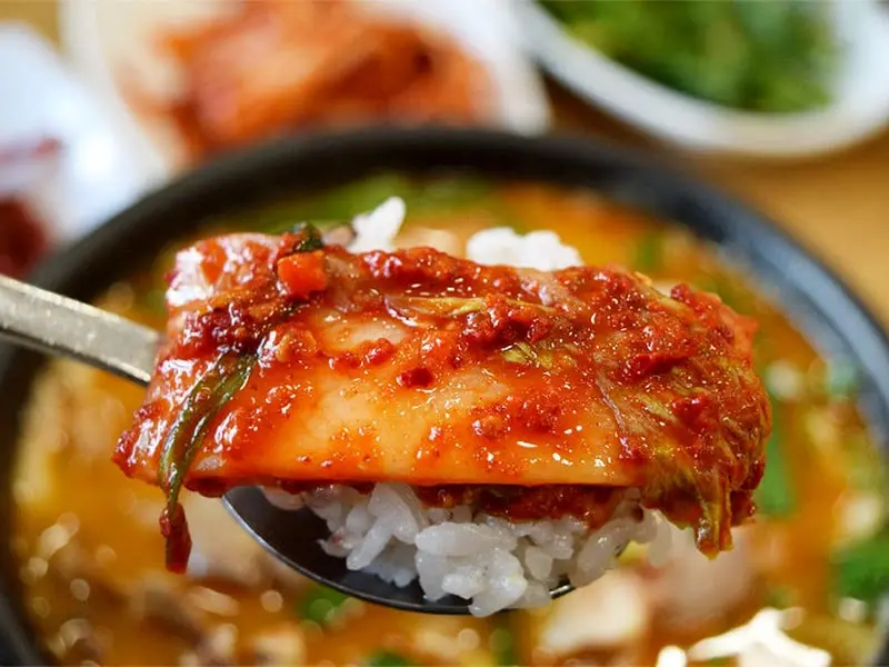 밥 위에 김치를 올려 한 입 가득 먹는 모습