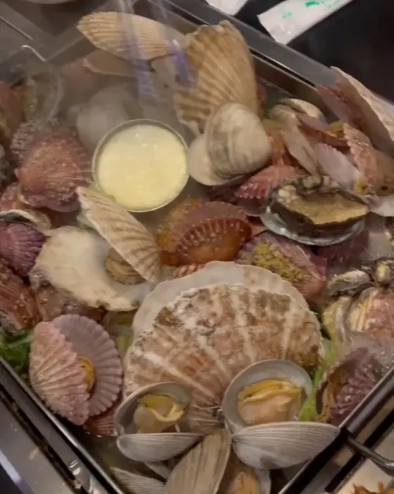 철판 조개 모듬찜에 담긴 다양한 조개류의 클로즈업 사진