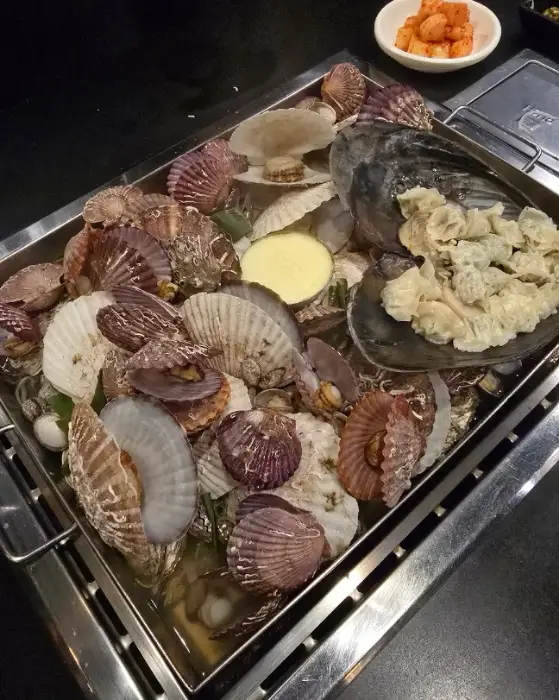 철판 조개 모듬찜에 칼국수 사리를 넣어 끓이는 모습