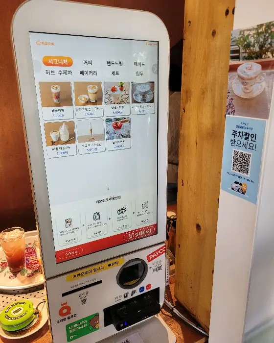 키오스크 화면에 다양한 메뉴 사진이 표시되어 있다.