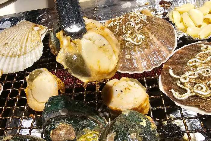 다양한 해산물과 조개류가 숯불 위에서 구워지는 모습