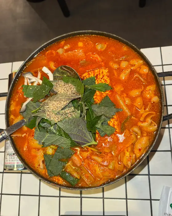 곱창전골 냄비 위로 덮인 푸른 쑥갓과 다른 채소들