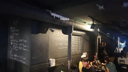어두운 조명의 실내 분위기와 벽에 적힌 메뉴판