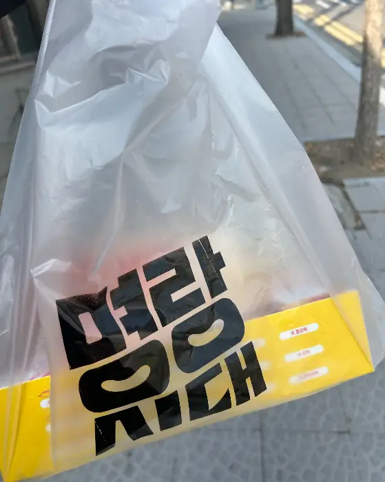 투명 비닐봉투에 담긴 핫도그 박스와 핫도그 사진
