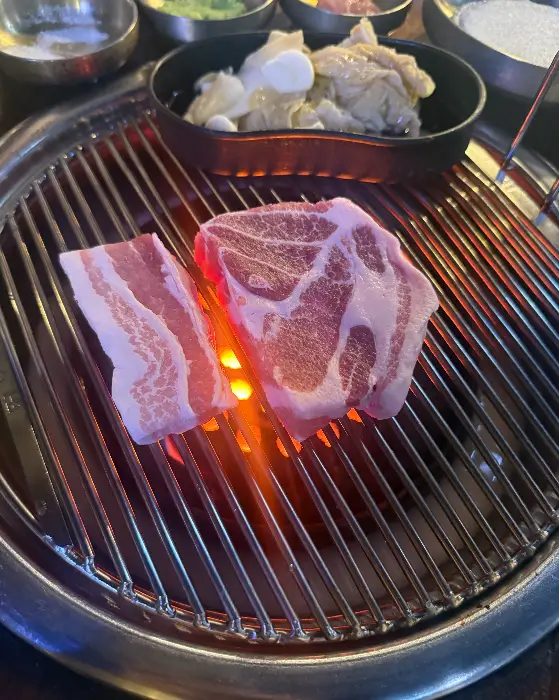 두툼한 삼겹살 덩어리가 연탄불 위에서 구워지는 모습