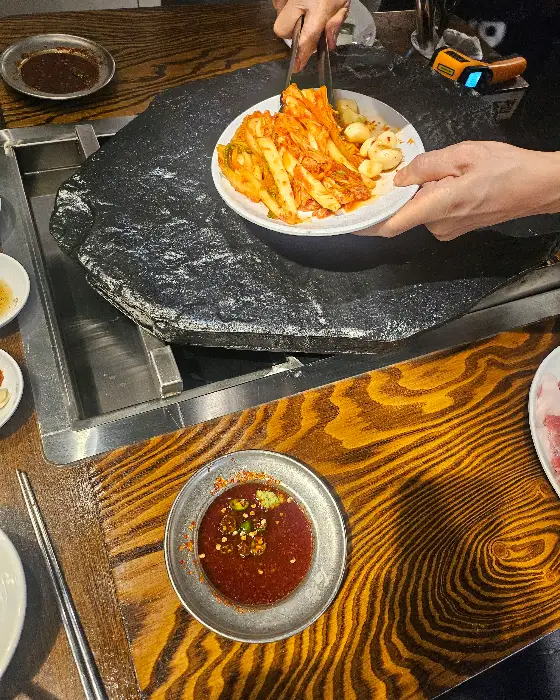 직원이 김치를 돌판에 올리는 모습