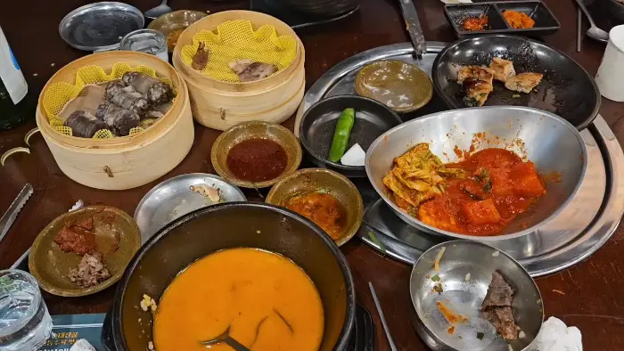 테이블 가득 차려진 다양한 순대국밥과 반찬, 술
