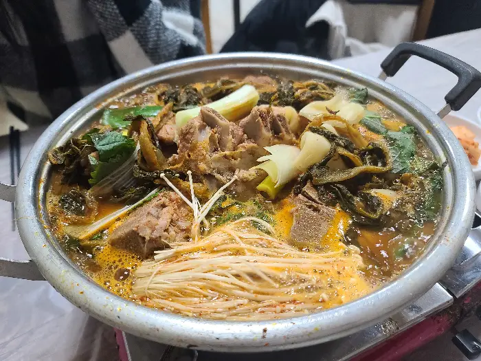 팔팔 끓고 있는 하지감자탕의 모습. 시래기, 팽이버섯, 돼지 등뼈가 푸짐하게 담겨 있다.