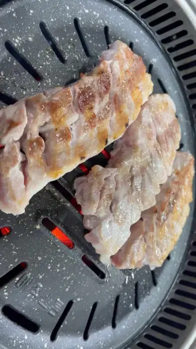 불판 위에서 구워지고 있는 두툼한 고기 덩어리