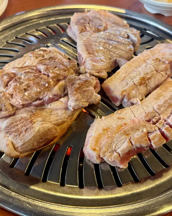 다양한 종류의 고기가 먹음직스럽게 불판 위에 올려져 있는 모습