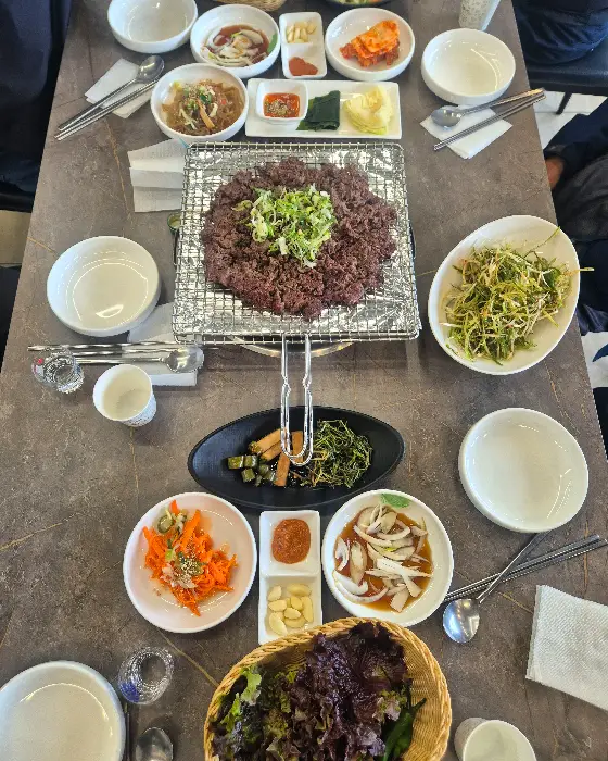 테이블에 차려진 다양한 음식들. 중앙의 불고기를 중심으로 여러 가지 반찬과 곁들임 메뉴가 보인다.