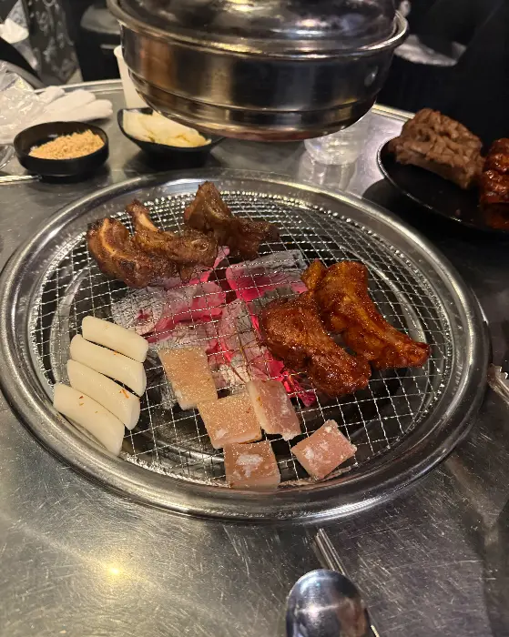 불판 위에서 구워지고 있는 쪽갈비와 떡, 옥수수 콘