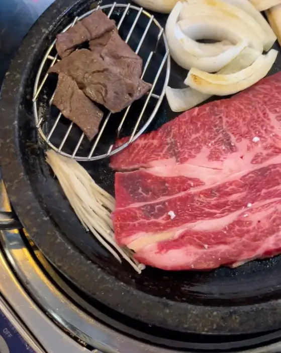 불판에 구워지고 있는 한우와 곁들임 재료들 사진