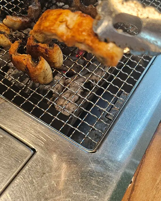 집게로 집어 올린 먹음직스러운 장어 조각