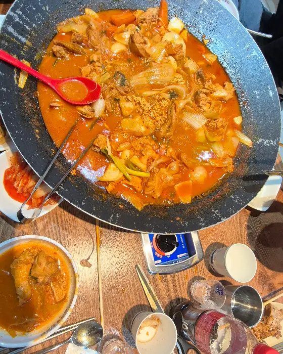 테이블 위 솥뚜껑 닭볶음탕과 반찬들