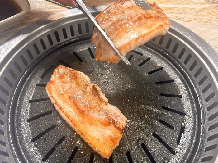 집게로 삼겹살 조각을 잘라내고 있는 모습