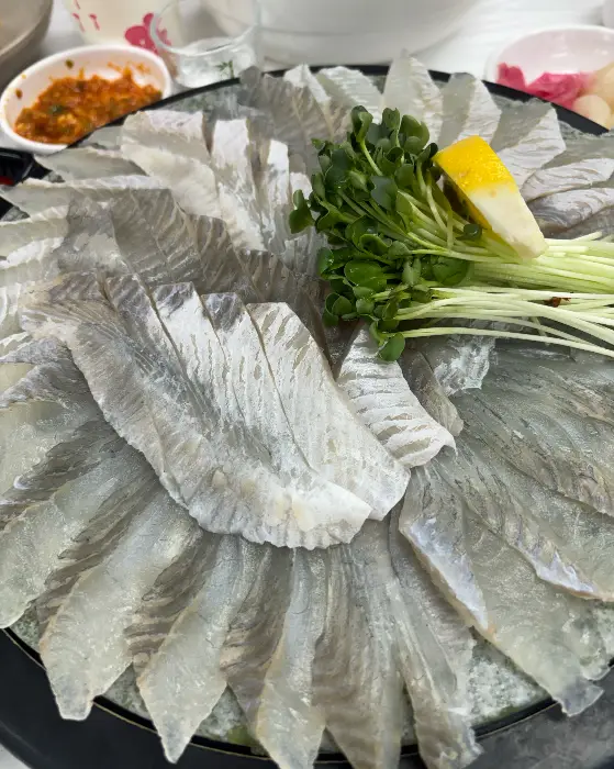 광어회로 보이는 얇게 썬 생선회가 동그랗게 배치된 모습