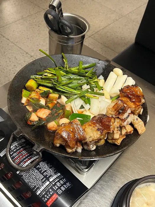 불판 위에 가지런히 놓인 곱창, 대창, 염통과 함께 볶아진 김치, 파, 마늘 등.
