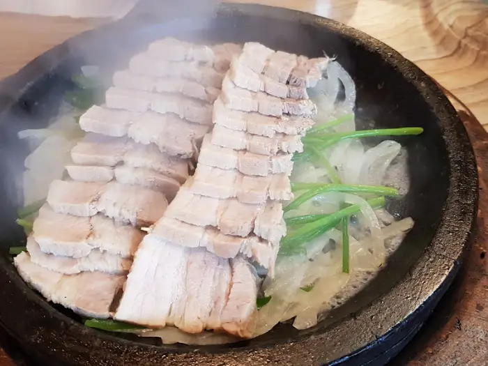 따뜻한 보쌈이 담긴 돌판과 곁들임 반찬