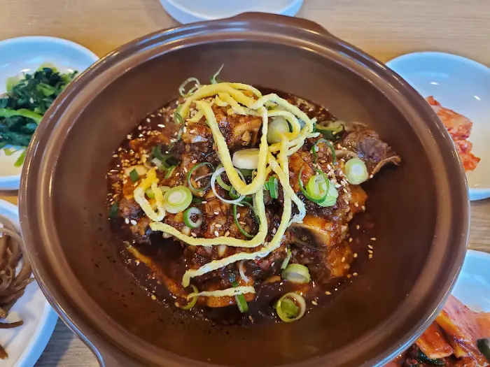 한 그릇 가득 담긴 찜갈비와 주변에 놓인 반찬들