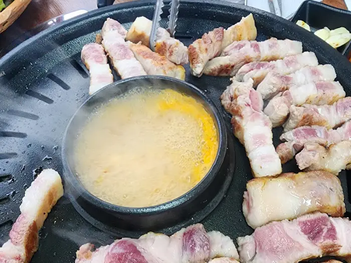불판 위에서 익어가는 고기와 된장찌개