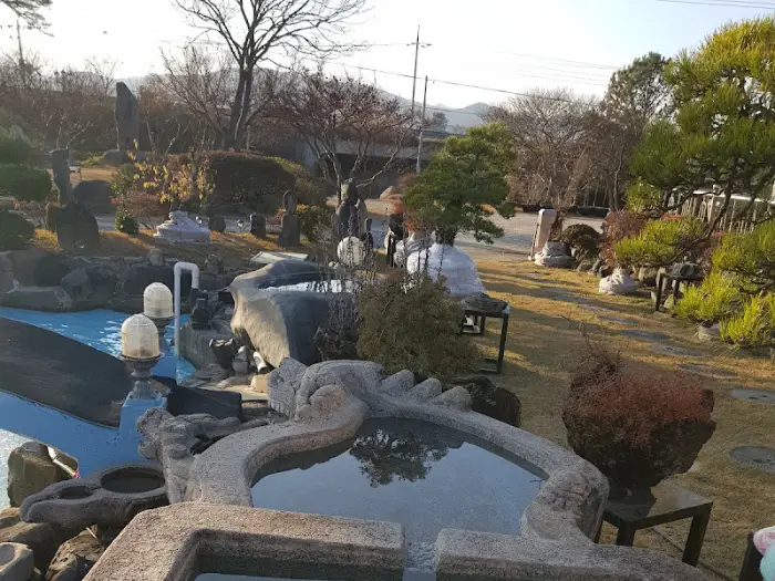 갤러리 카페 정원 전경, 다양한 수석과 조형물, 나무들이 어우러진 모습