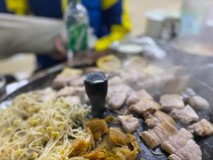 솥뚜껑 위에서 익어가는 삼겹살과 각종 채소