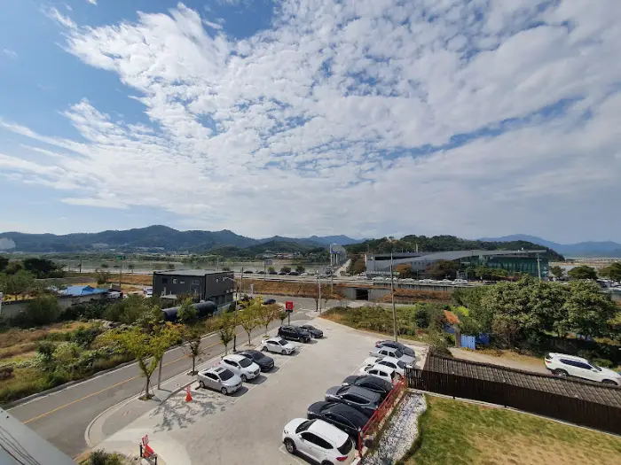 Panoramic view of a parking lot with many cars, overlooking a valley with mountains in the distance under a partly cloudy sky
