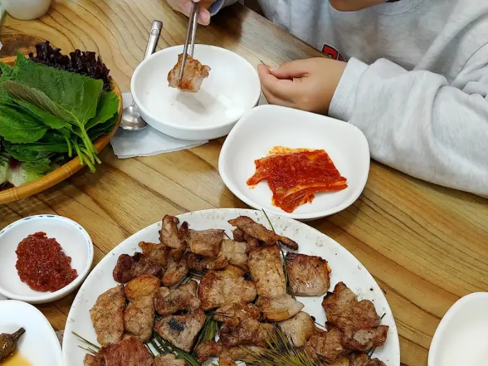 아이의 손이 숯불구이 조각을 집는 모습과 주변의 음식들