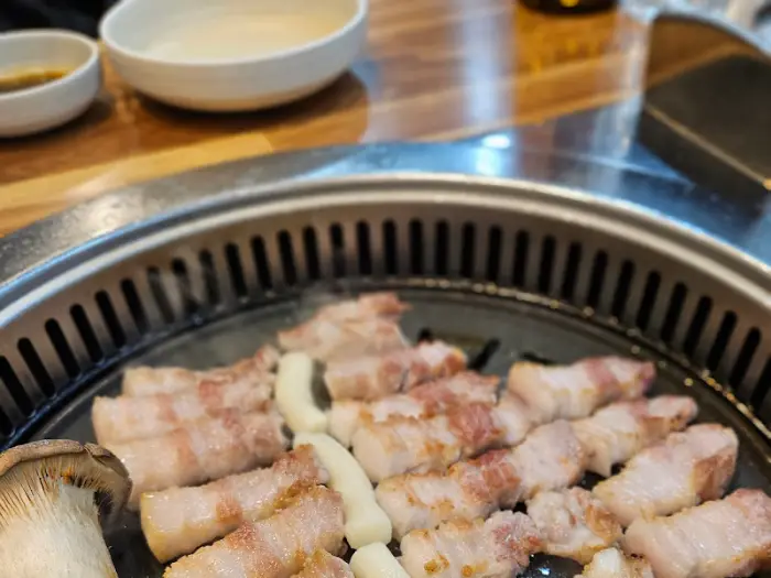 삼겹살과 떡, 버섯이 불판 위에서 익어가고 있다.