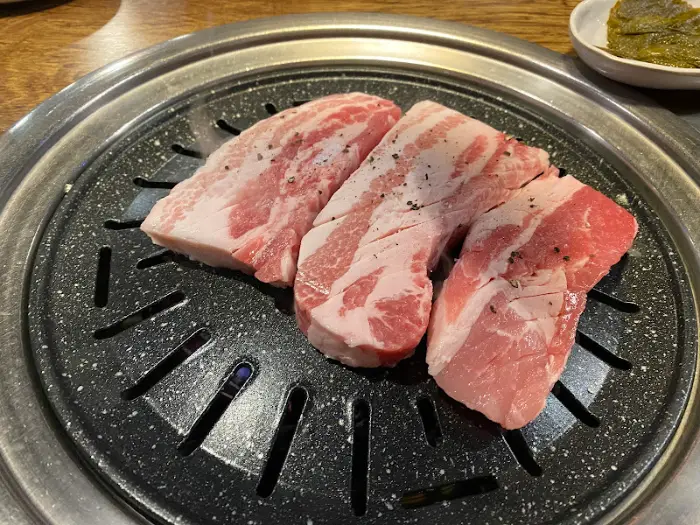 불판 위에서 익어가고 있는 세 덩이의 두툼한 삼겹살