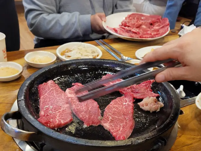 집게로 집어 익히는 중인 한우 고기