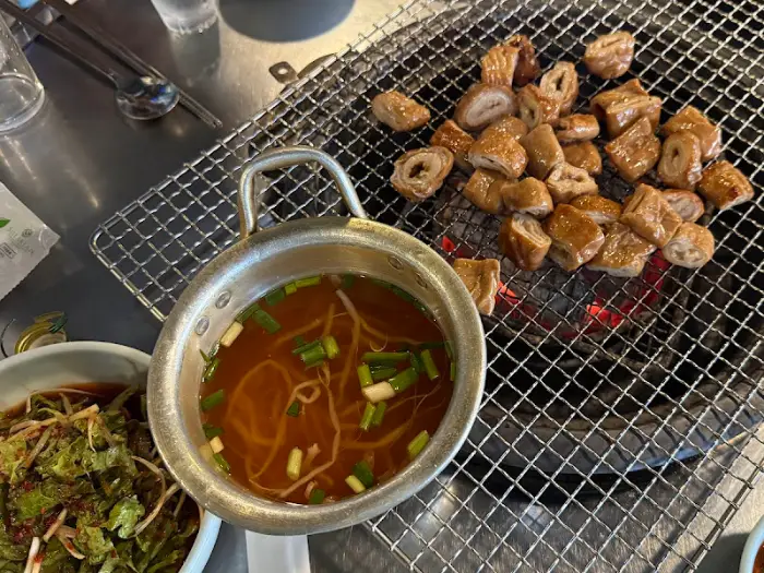 불판 위에서 익어가는 돼지막창과 곁들임 소스