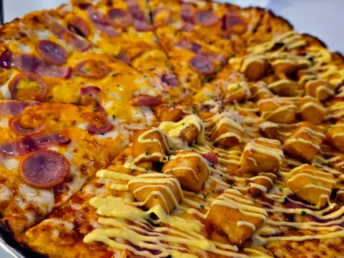 두 가지 맛 피자의 모습, 왼쪽은 햄과 치즈, 오른쪽은 튀김 조각과 소스가 올라가 있습니다.