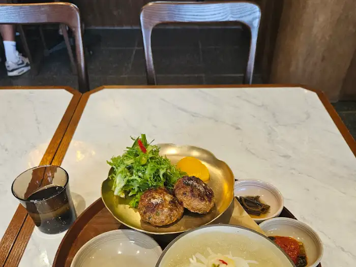 테이블에 놓인 떡갈비와 동치미 국수, 샐러드