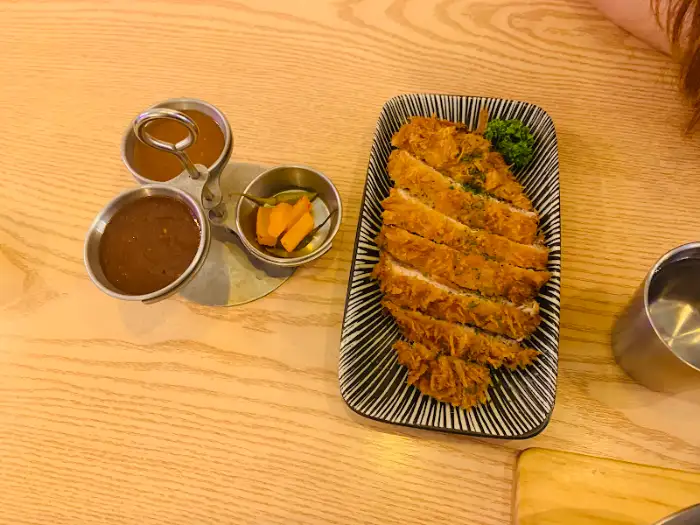 접시에 예쁘게 플레이팅된 돈까스와 곁들임 소스, 곁들임 반찬