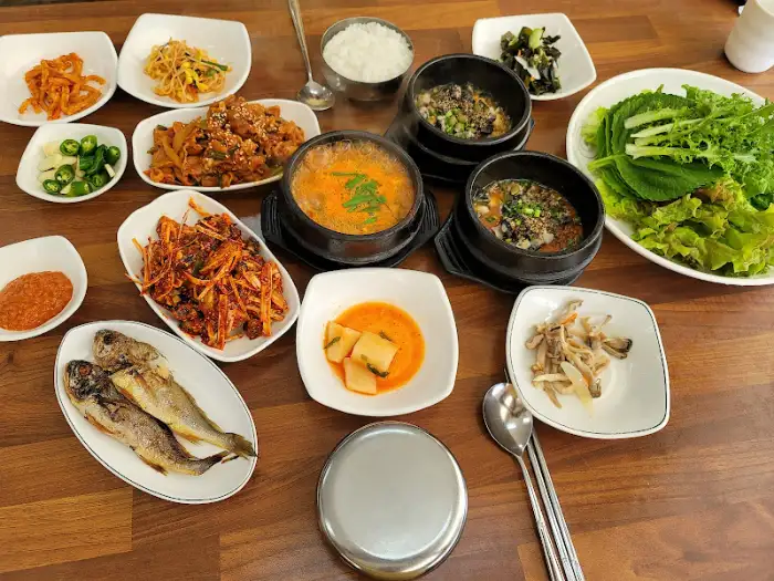 싱싱한 쌈 채소와 우렁이 쌈장, 밥을 함께 싸 먹는 모습. 풍성한 한 끼를 보여준다.