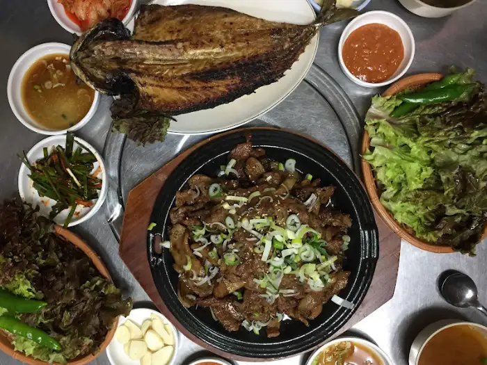 돼지불백, 고등어구이, 쌈 채소, 밥, 밑반찬 등이 차려진 푸짐한 식탁