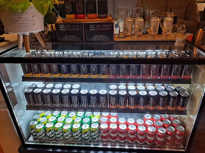 냉장고에 진열된 다양한 종류의 수제 맥주 캔들이 보입니다.