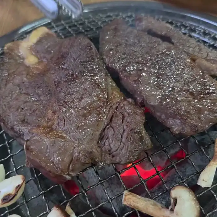 불판 위에서 익어가는 고기 두 점