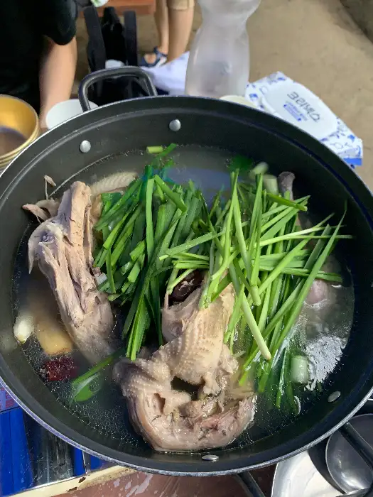 뜨겁게 끓고 있는 닭백숙. 닭고기가 푸짐하게 들어있고 파가 듬뿍 올라가 있다.