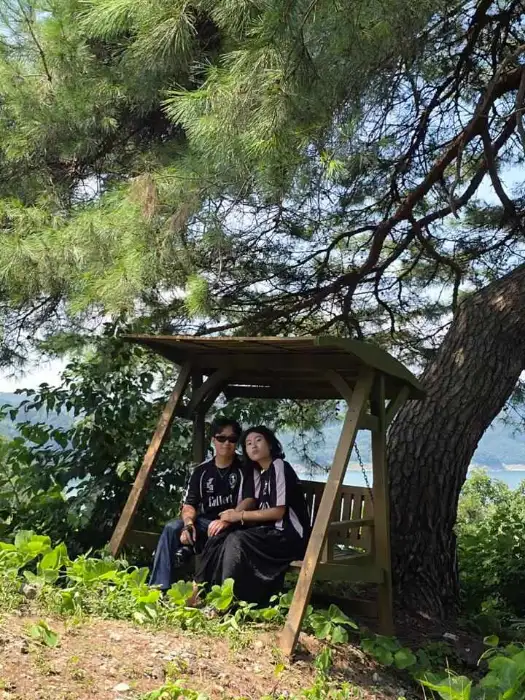 나무 아래 벤치에 앉아 있는 두 사람