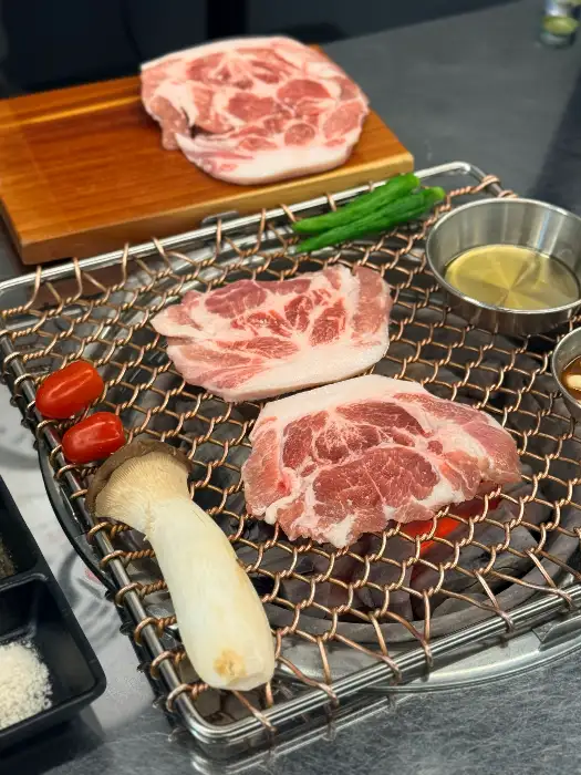 신선한 돼지고기 부위들이 숯불 위에서 구워지는 모습